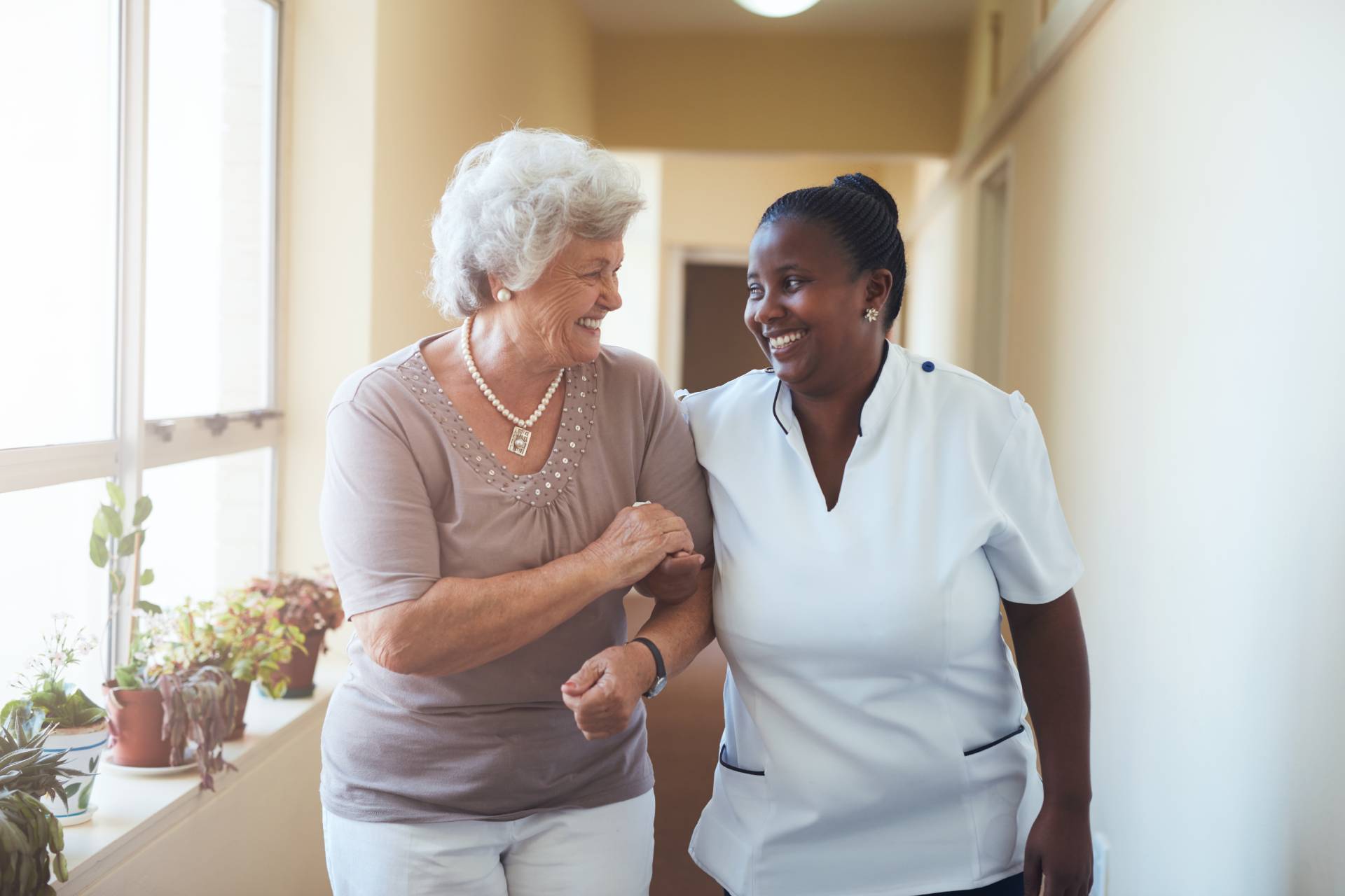 A caregiver walking down a hallway with a senior.