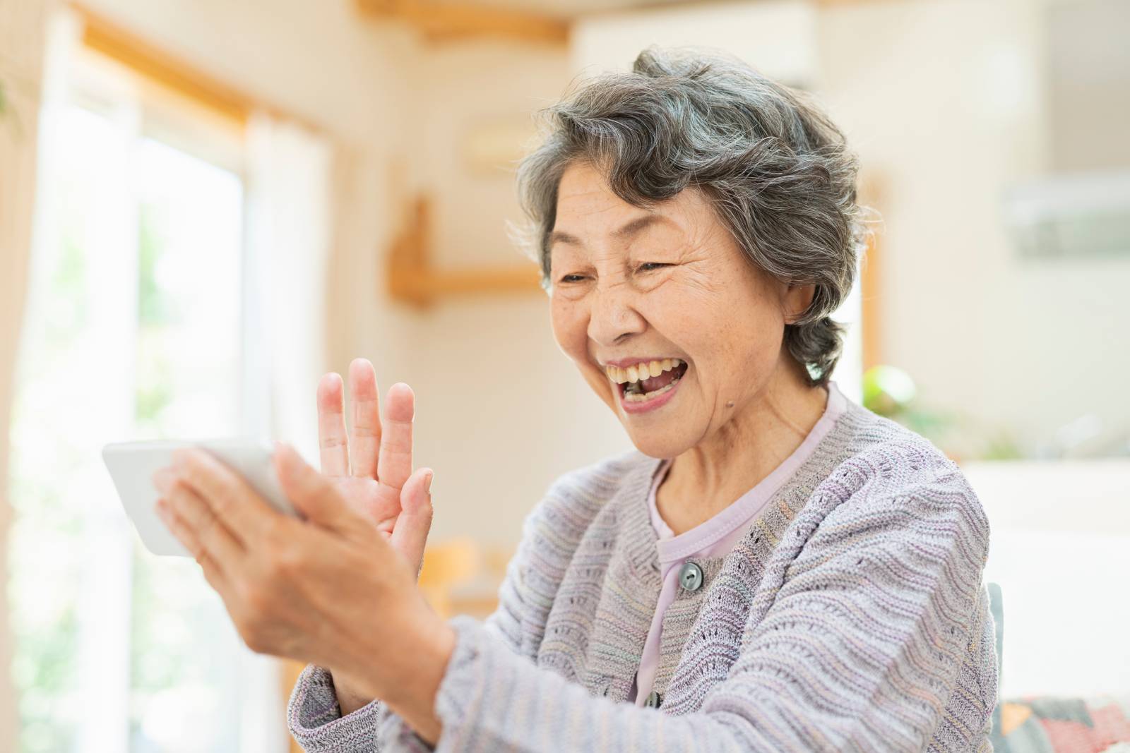 A senior smiling at her phone.