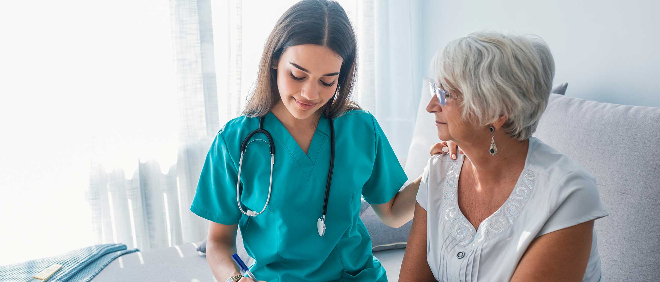 A female senior sitting with a caregiver.