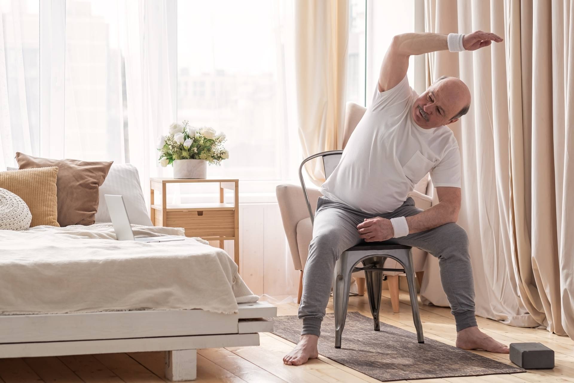 Senior man doing a seater skater twist in his bedroom.