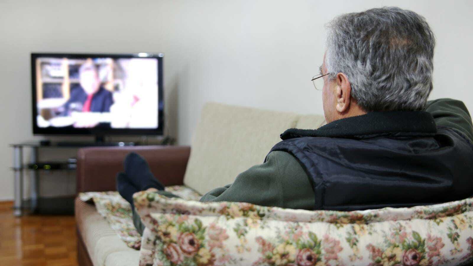 Senior man watching a movie on his couch.