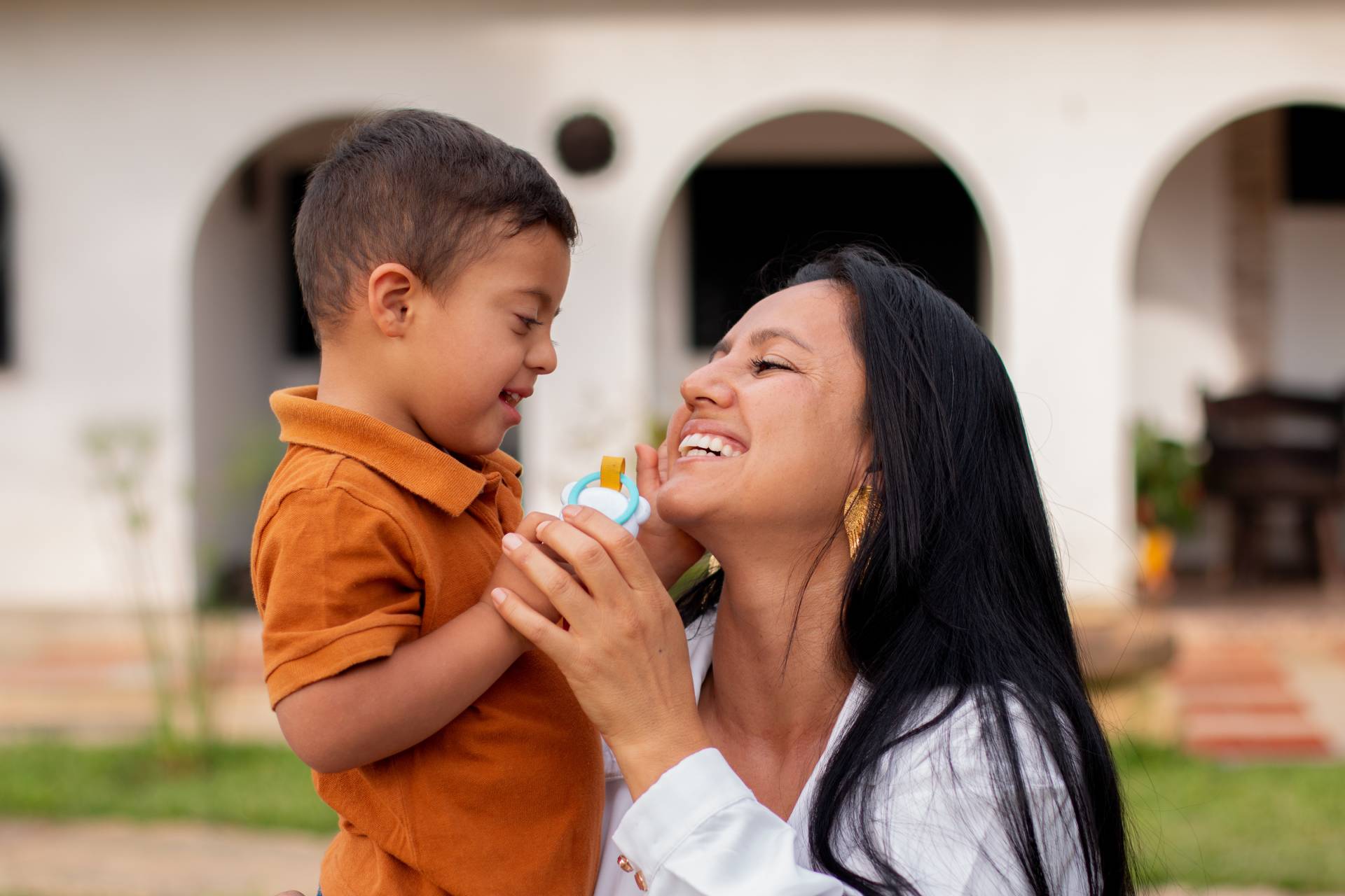 A mother and her son with Down syndrome share a joyful moment outside their home.