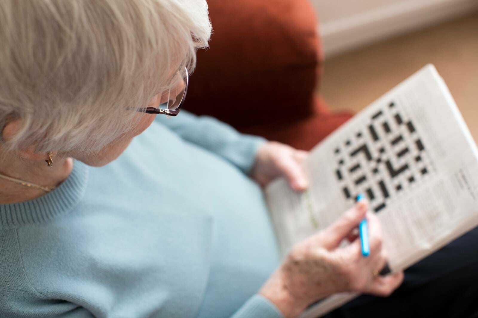 Senior with dementia doing a crossword cognitive activity.