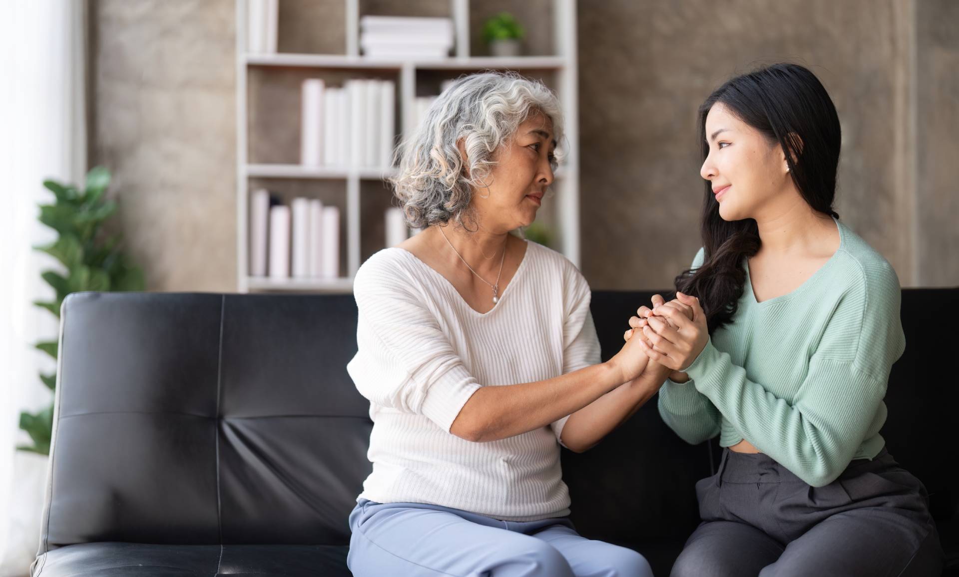 A mother and daughter sitting on a couch talking about the aging parent expecting too much.