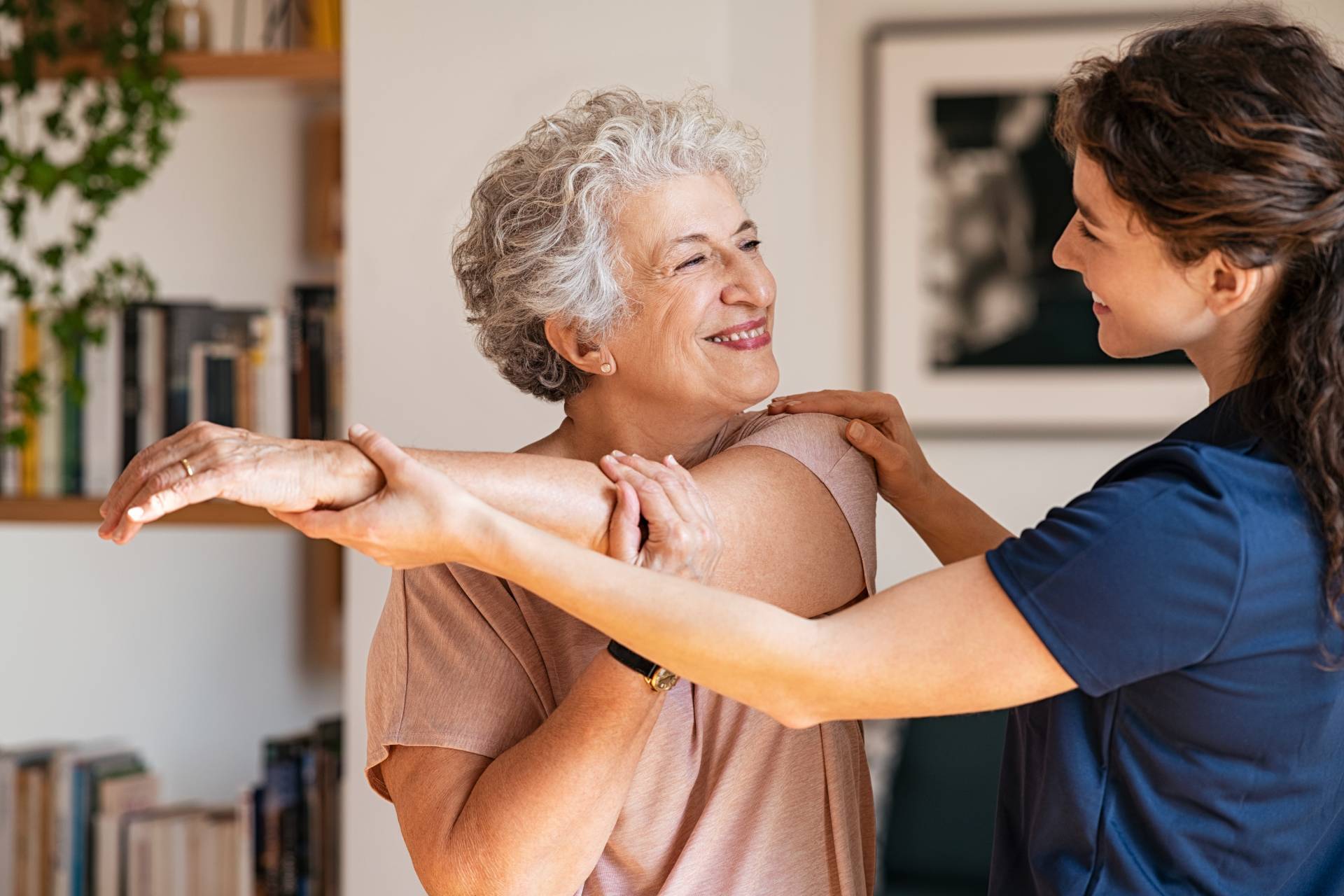 Senior woman stretching with a caregiver.
