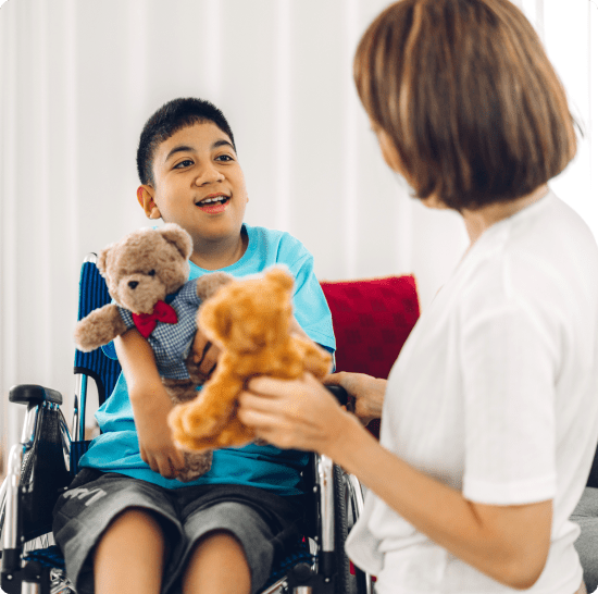 A boy and caregiver playing with teddy bear