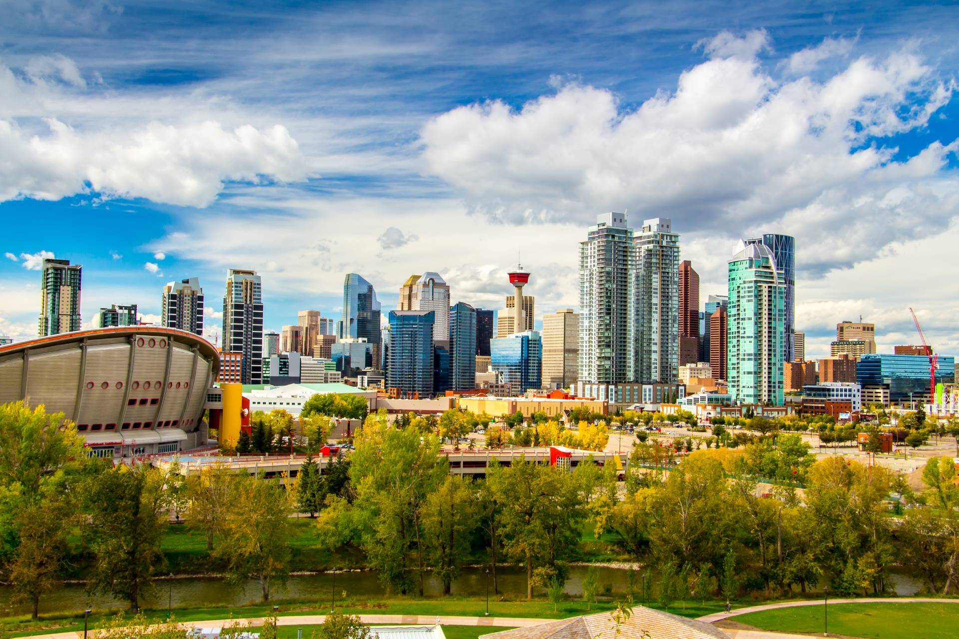Calgary skyline with the Calgary Tower and Scotiabank Saddledome arena, framed by the Bow River and trees in early autumn colour