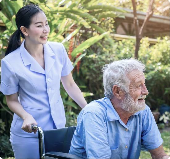 Ready to Get Started with Live-In Care_-image Caregiver pushing a smiling elderly man in a wheelchair through a garden
