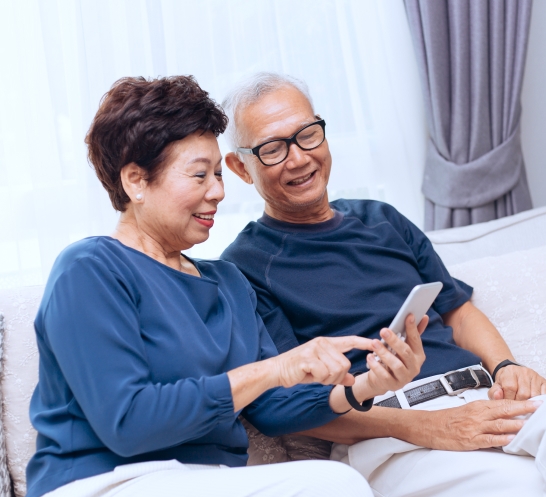 Elderly couple sitting together looking at a smartphone screen