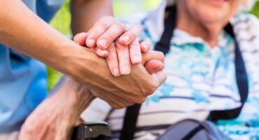 home-care-services-supported-by-government A caregiver holding the hand of an elderly woman