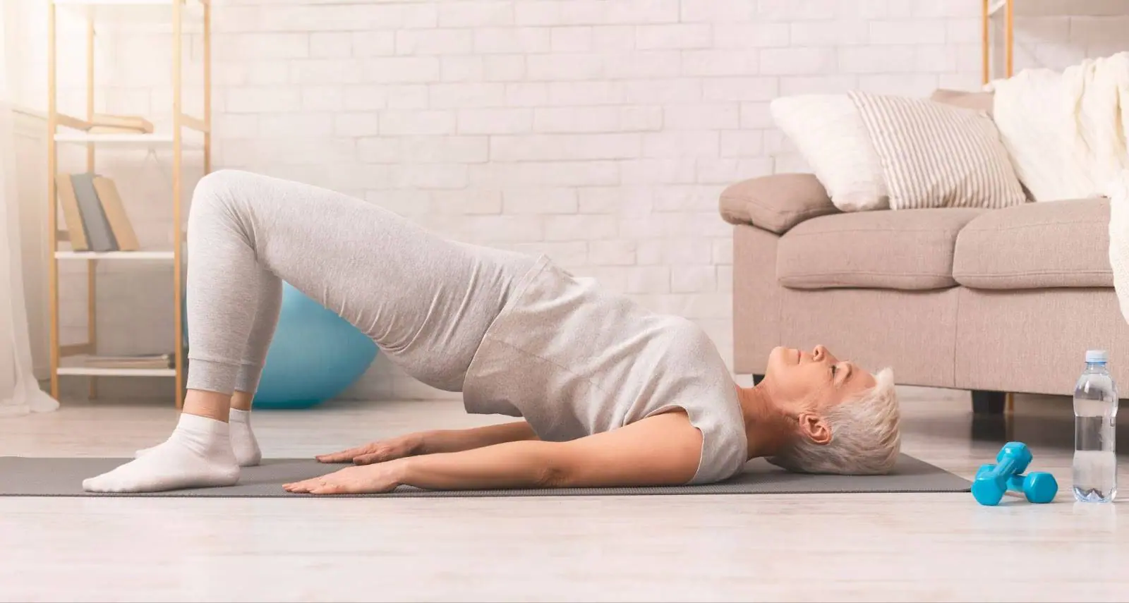 Old woman doing a bridge in her living room. 