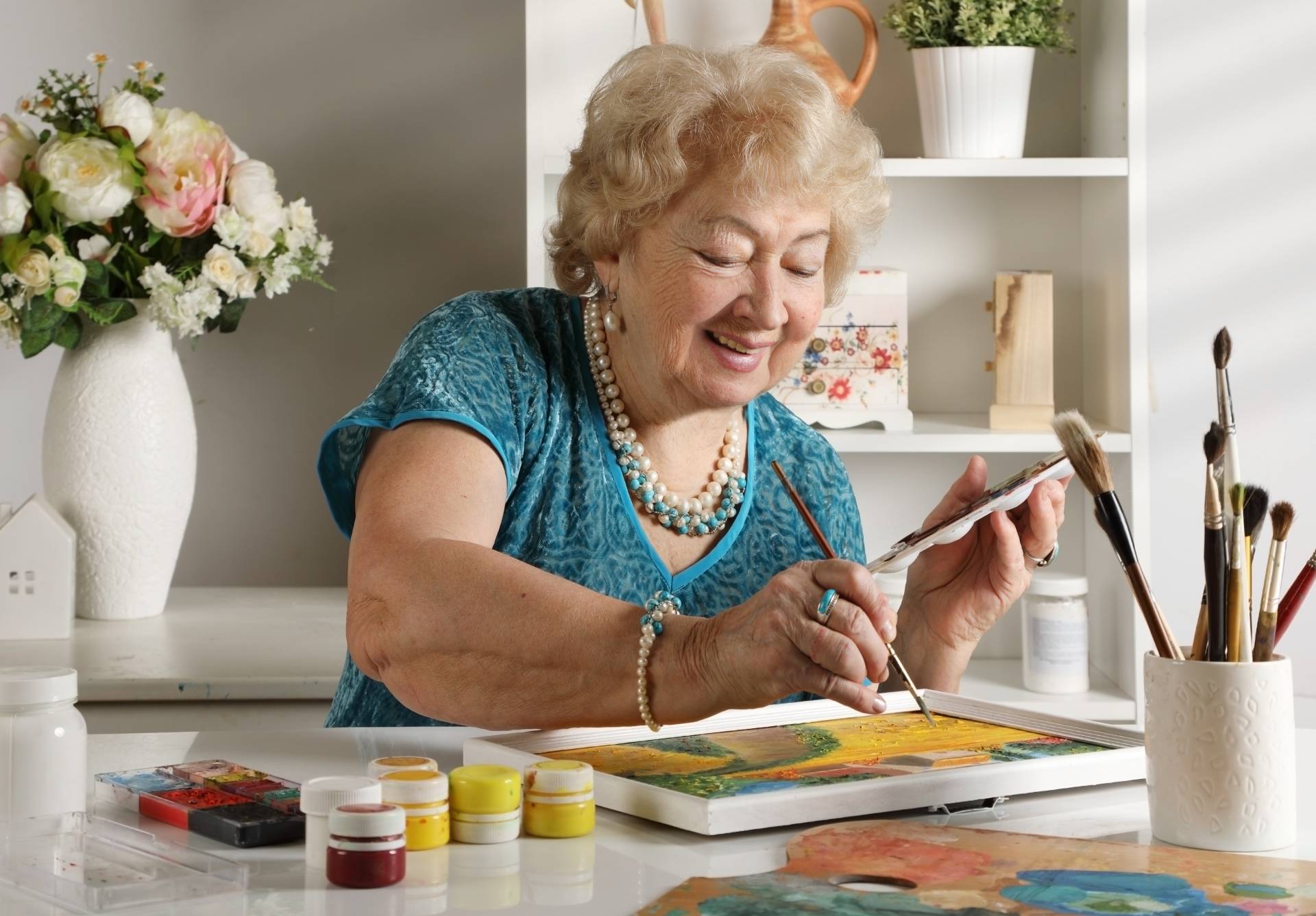 An elderly woman painting a paint-by-number at her dining room table